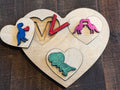 Peekaboo puzzle highlighting dinosaur-themed letters and geometric heart shapes, promoting letter recognition and fine motor skill development in young learners