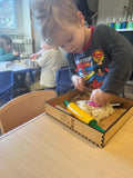 Focused child identifying shapes in Playdough with vibrant tools, showcasing developmentally appropriate tactile play in a daycare environment.