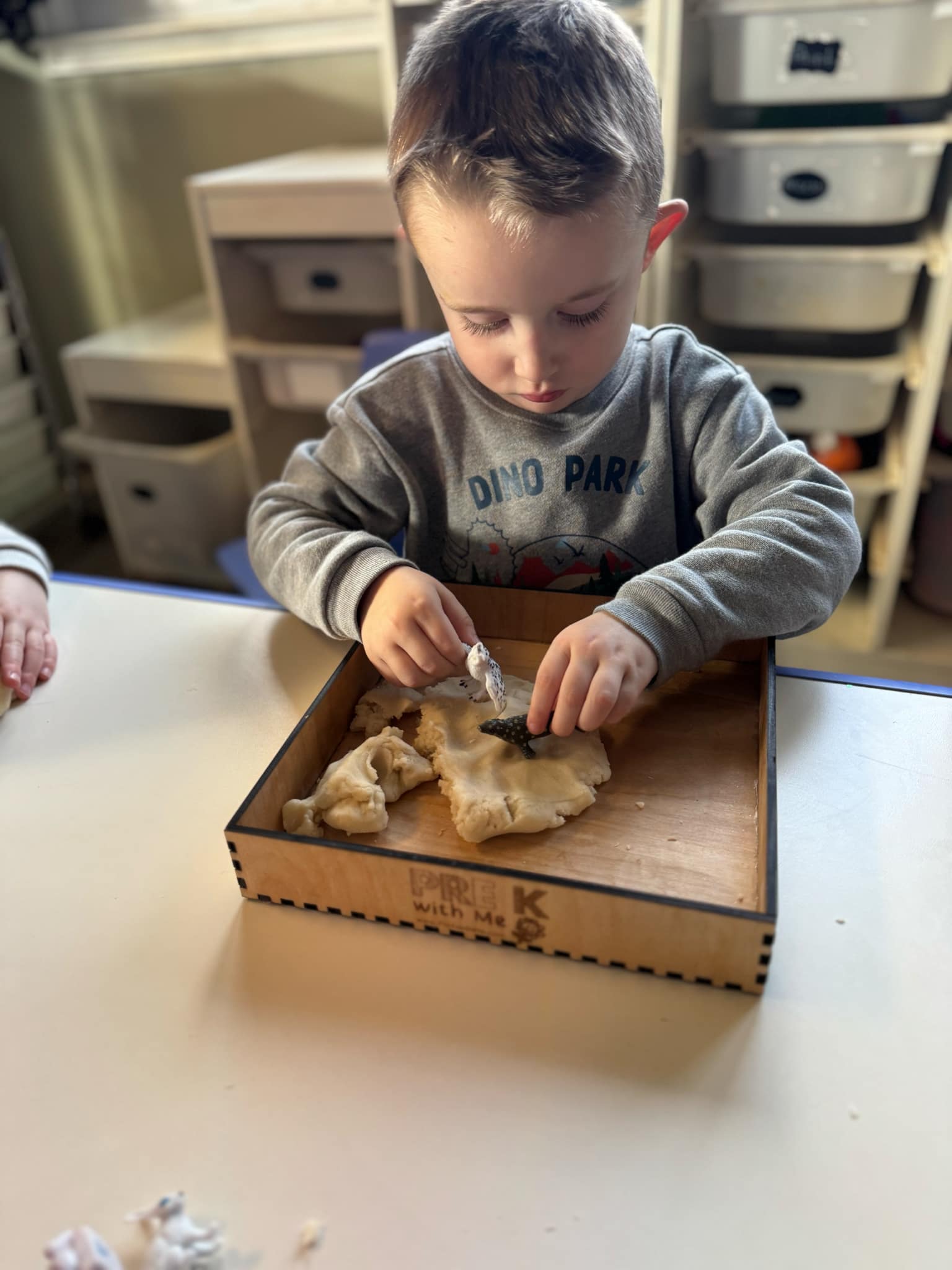 A pre K student using a sensory bin to explore textures, develop fine motor coordination, and build early learning skills in a fun and interactive way.