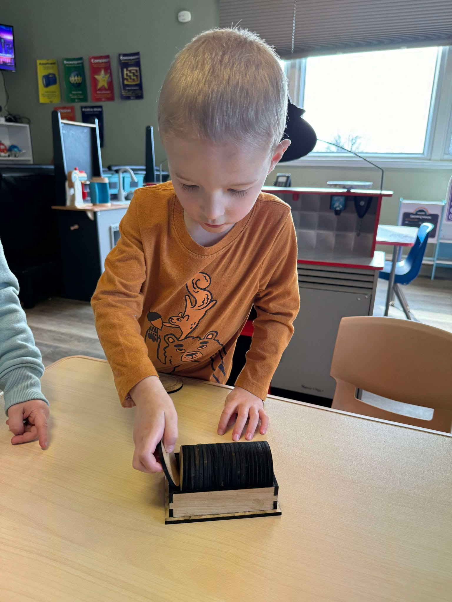 Child stacking and organizing wooden shape tiles from the Basic Shapes Matching Game, promoting fine motor skills and independent exploration in preschool or homeschool.