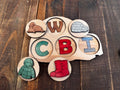 Igloo-shaped peekaboo puzzle featuring W for Walrus, C for Coat, B for Boot, and I for Igloo, with colorful wooden letters and symbols for preschool learning.